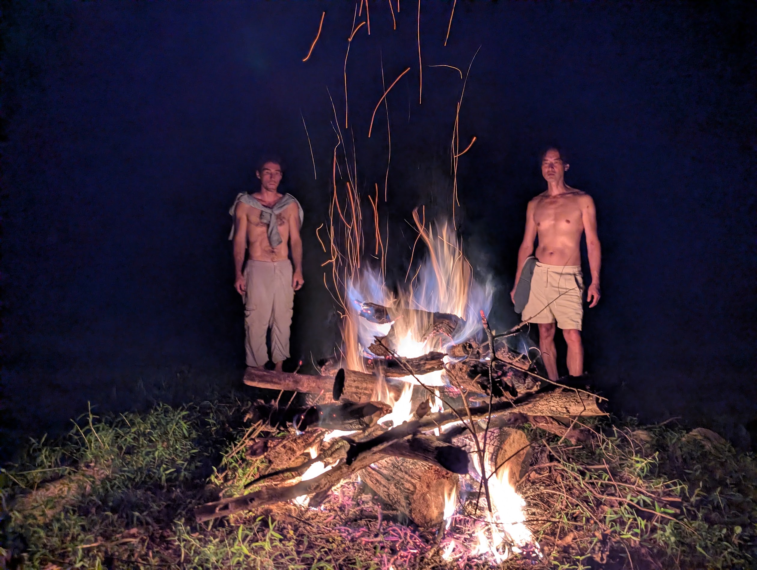 Two people standing beside a blazing ceremonial fire at night, from Four Sacred Fires